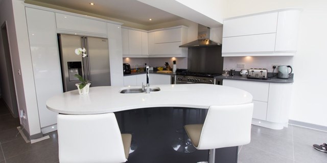 Bespoke kidney shaped kitchen island complete with stainless steel sink, taps and intergrated dishwasher.